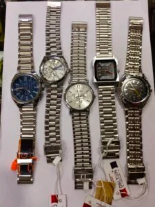 Men’s silver metal belt wrist watches collection with multiple dial designs displayed on a white surface